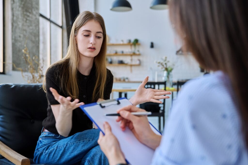Young teenager girl talking to therapist about eating disorders in teenagers.