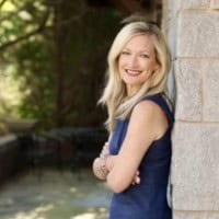 Smiling woman outdoors near a tree, representing mental health and wellness.