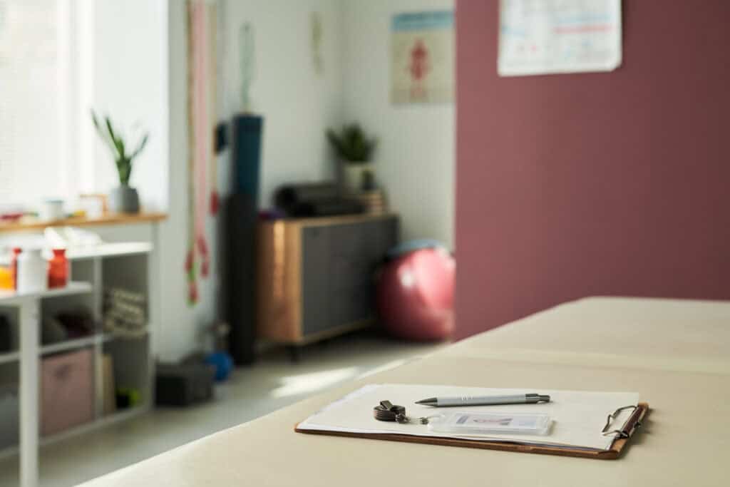 Therapist's office with clipboard, pen, and medical tools on desk.