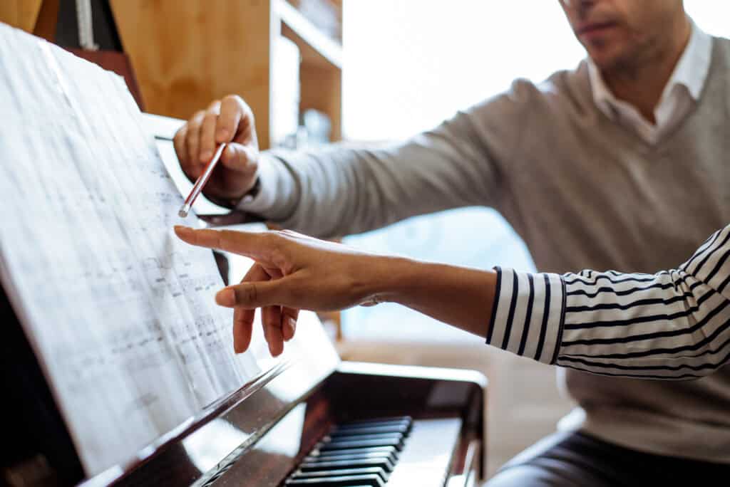 Music therapist and client discussing sheet music at piano.