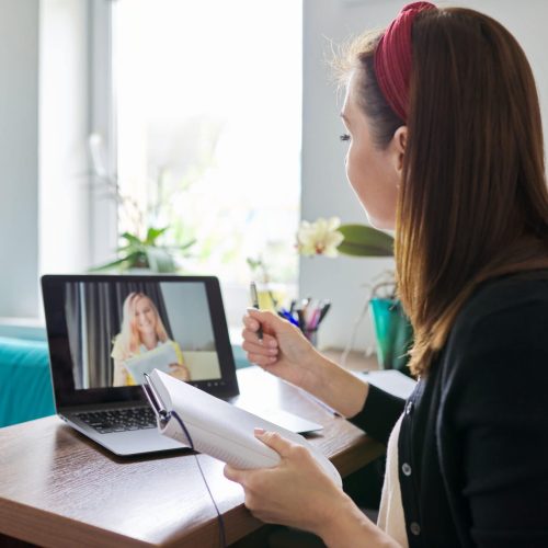 Woman teacher teaching at home online, distance learning. Female sitting at home at table with laptop on virtual meeting with teenage student, video call. E-learning modern technologies in education