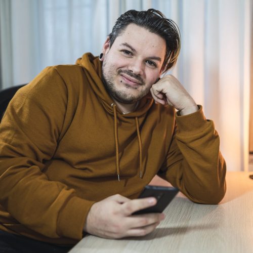A selective focus shot of a cool cheerfulguy with piercings using his smartphone in a room